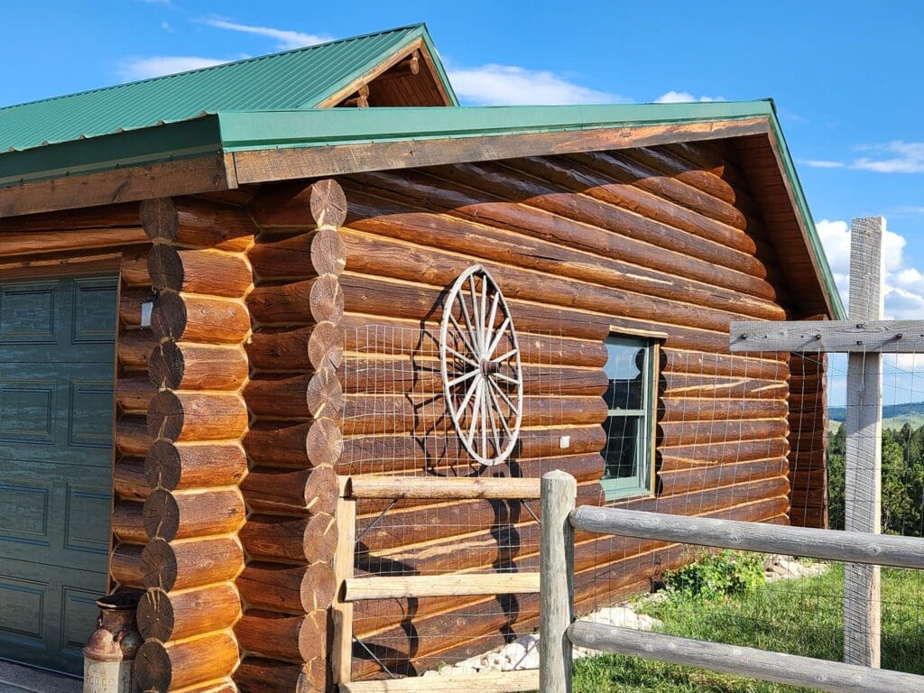 cabin with log fence posts and wagon wheel on exterior wall
